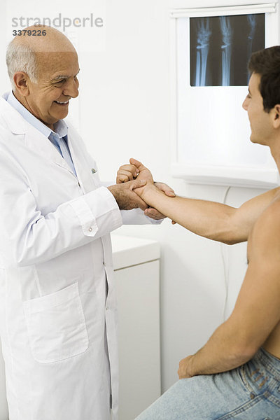 Arzt untersucht das Handgelenk des Patienten