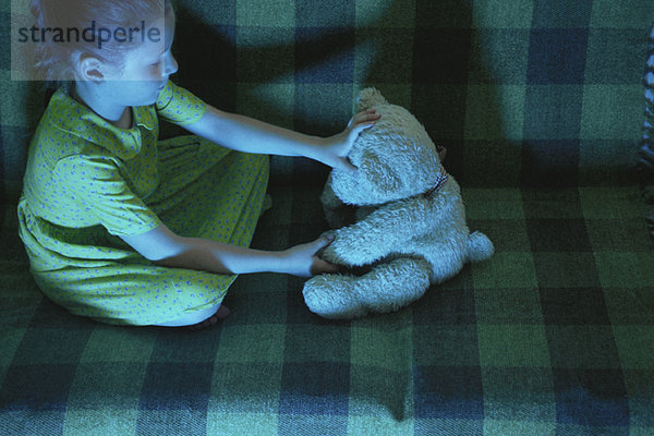 Kleines Mädchen sitzt auf dem Sofa mit Teddybär