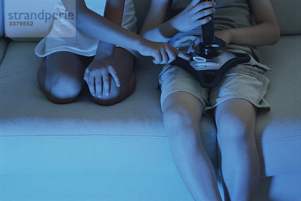 Kinder spielen zusammen Videospiel auf dem Sofa  Ausschnittansicht