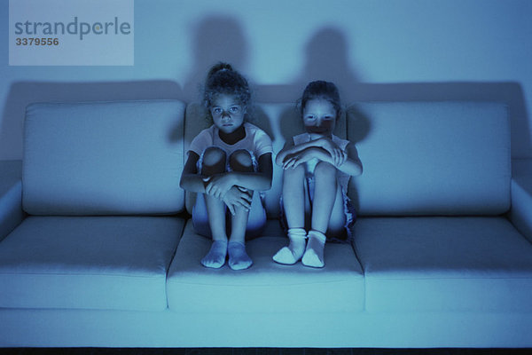 Zwei Mädchen  die nachts zusammen auf dem Sofa fernsehen.