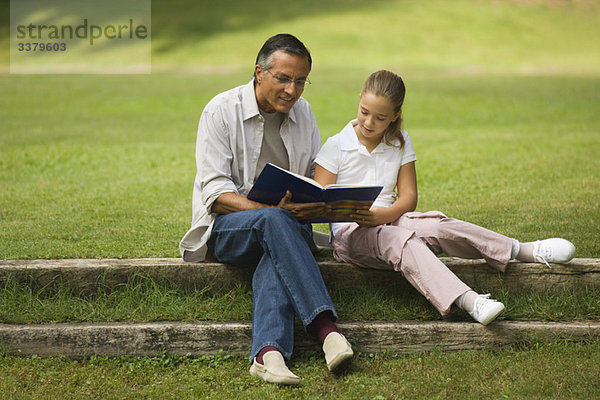 Vater und Tochter beim gemeinsamen Lesen im Park