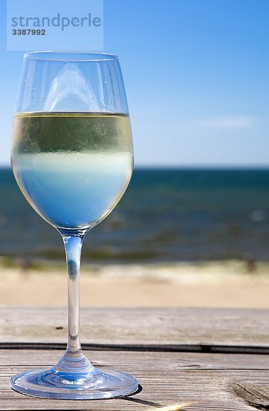 Glas mit Weißwein steht auf Holzbrett  Meer im Hintergrund  Wenningstedt-Braderup  Sylt  Deutschland