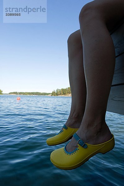 Frau baumelnd ihre Beine über dem Wasser  Schweden.