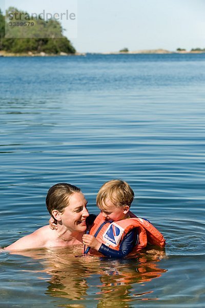 Boy in eine Schwimmweste Baden mit seiner Mutter  Schweden.