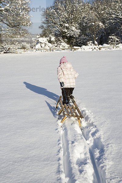 Junges Mädchen zieht Schlitten im Schnee