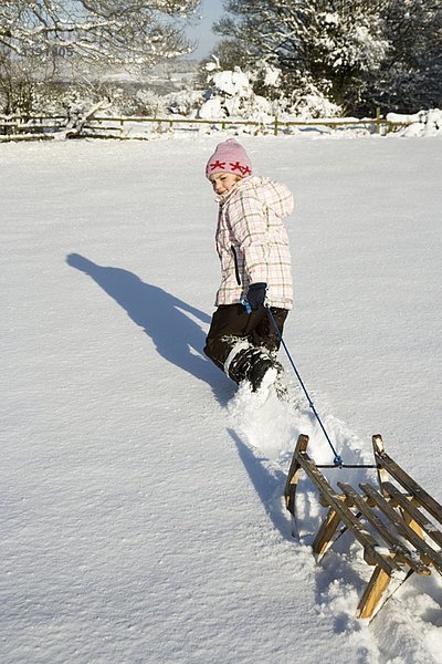 Junges Mädchen zieht Schlitten im Schnee