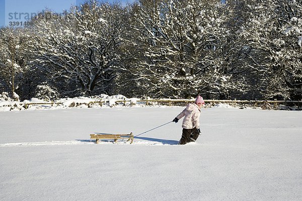 Junges Mädchen zieht Schlitten im Schnee