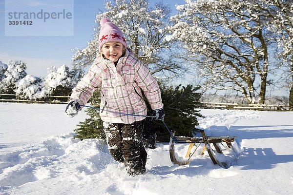 Mädchen zieht Schlitten im Schnee