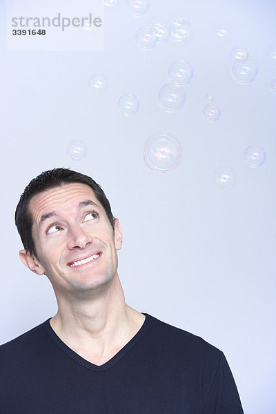 lächelnder Mann mit Blick auf Blasen