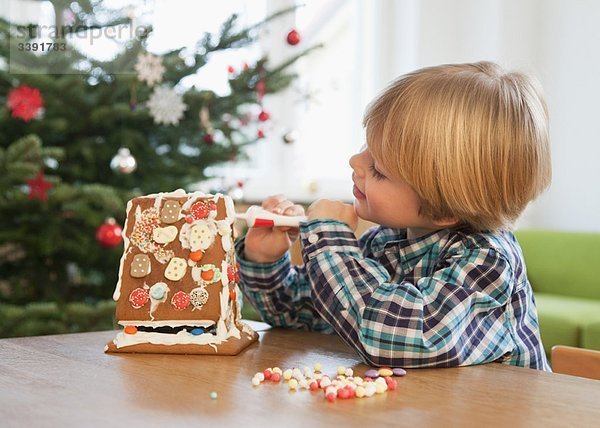 Junge dekoriert Lebkuchenhaus