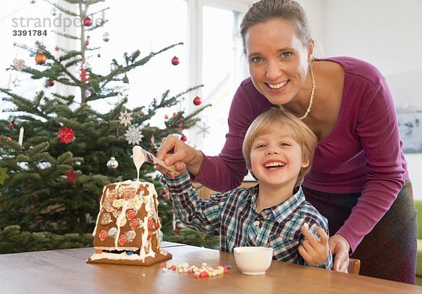 Mutter  Junge dekoriert Lebkuchenhaus