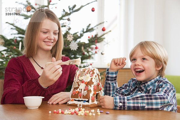 Mädchen  Junge dekoriert Lebkuchenhaus