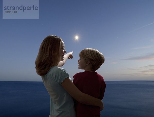 Junge und Mädchen  die den Mond aufgehen sehen.