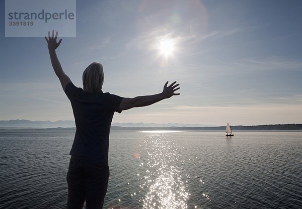 Mann  der den Sonnenuntergang über einem See beobachtet.