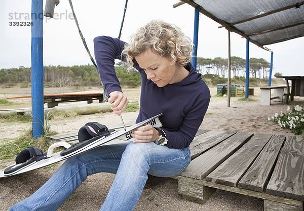 Frau  die ihre Flosse auf dem Kiteboard anbringt.