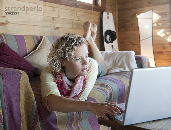 Frau in einem Strandhaus  mit Hilfe des Computers