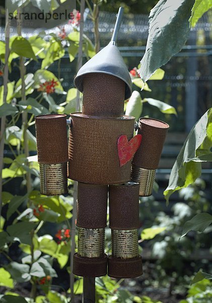 Ein Blechmann  der in einem Garten hängt.