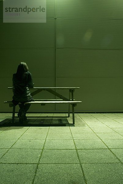 einsame Frau auf der Bank sitzend