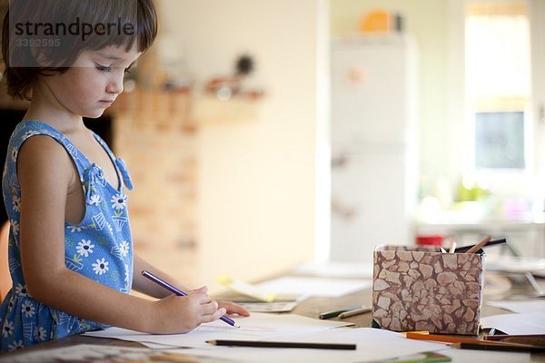 kleines Mädchen beim Zeichnen am Küchentisch