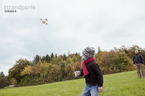 Vater beobachtet Sohn beim Drachenfliegen