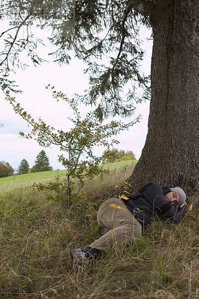 Mann schläft unter einem Baum