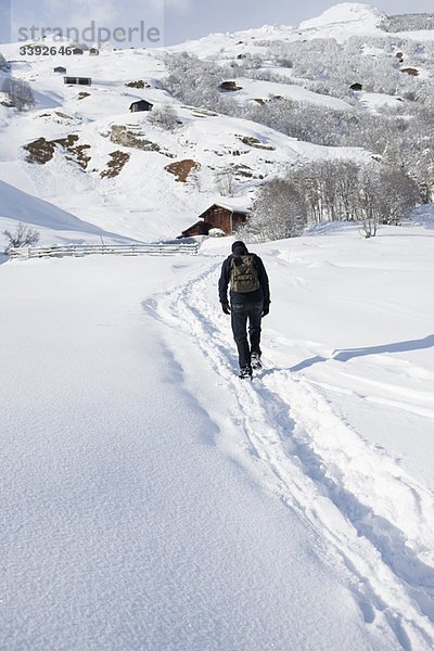 Mann  der durch Schnee in der Landschaft wandert