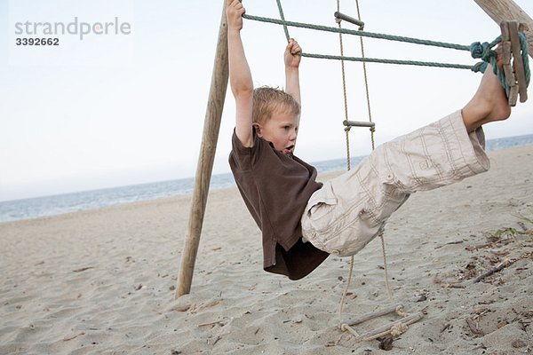 Junge auf einer Schaukel am Strand