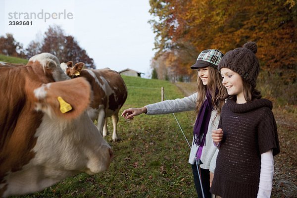 Zwei Mädchen auf einer Weide mit Kühen