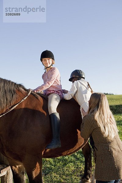 Frau hilft Mädchen zu Pferd