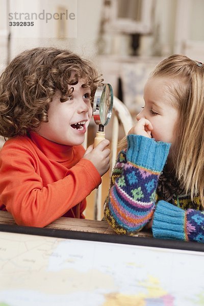 zwei Kinder spielen mit Lupe