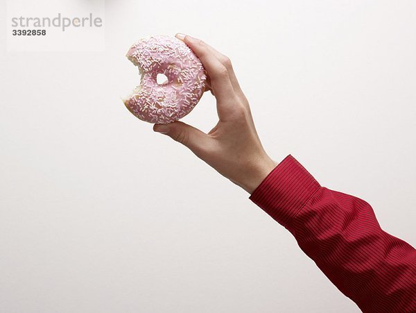 Eine Hand  die einen Donut hält.