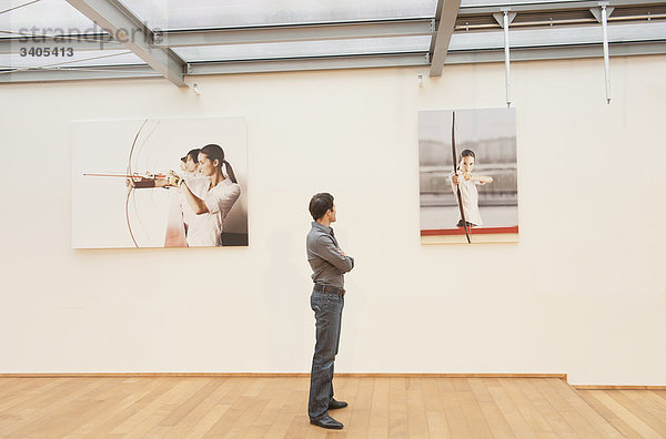 Ein Mann guckt Fotografien an der Wand an