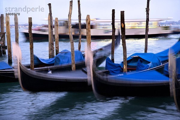 Festgemachte Gondeln  Boot fährt im Hintergrund  Venedig  Italien