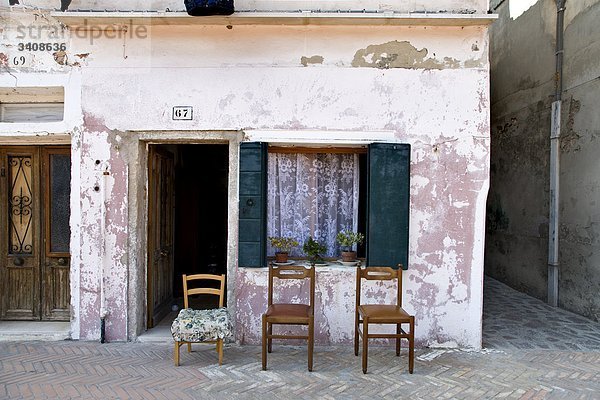 Drei Stühle vor einem alten Haus  Burano  Italien