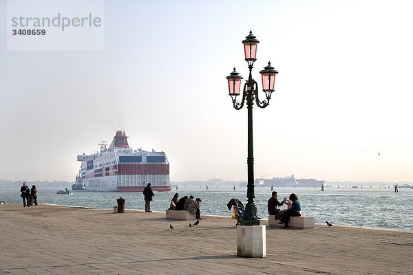 Menschen auf einer Uferpromenade in Venedig  Fähre im Hintergrund  Italien