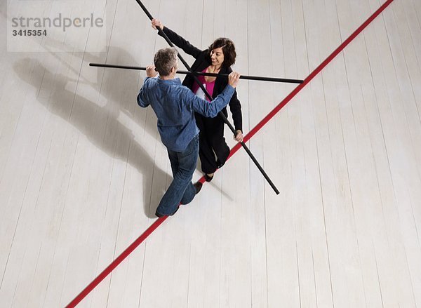 Mann und Frau balancieren auf dünner roter Linie