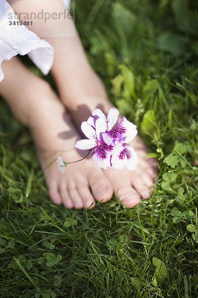 Kinderfüße mit einer Blume