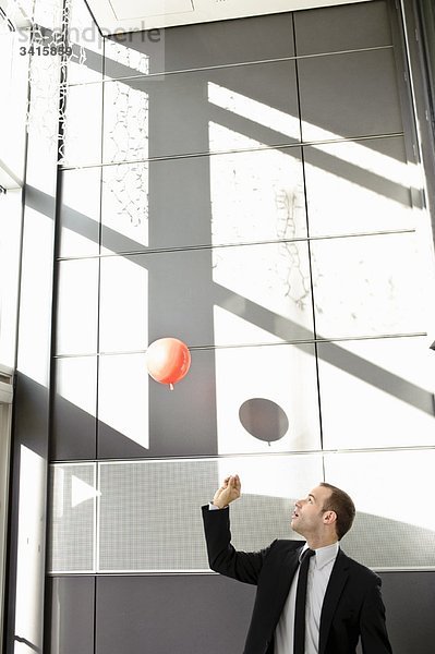Mann setzt Ballon im Büro frei