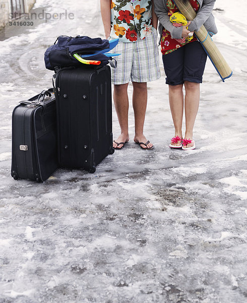 Paar im Schnee stehend mit Koffern