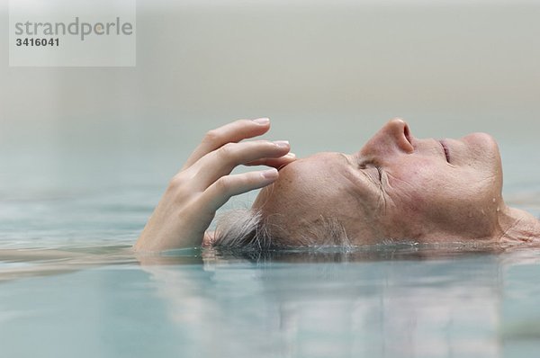 Ältere Frau beim Meditieren im Pool