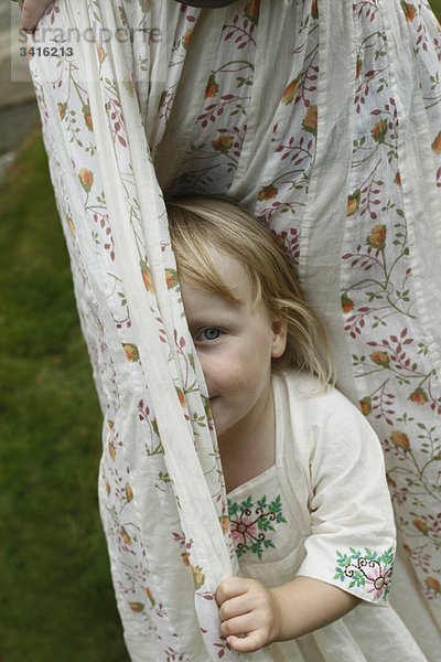 Kleines Mädchen versteckt sich hinter Vorhängen
