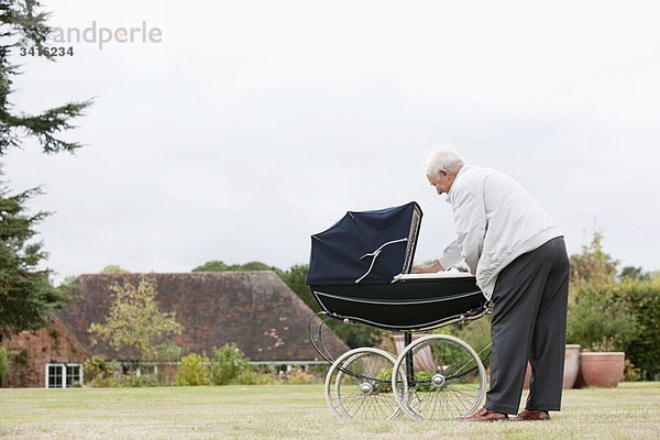 Großvater schaut Baby im Kinderwagen an