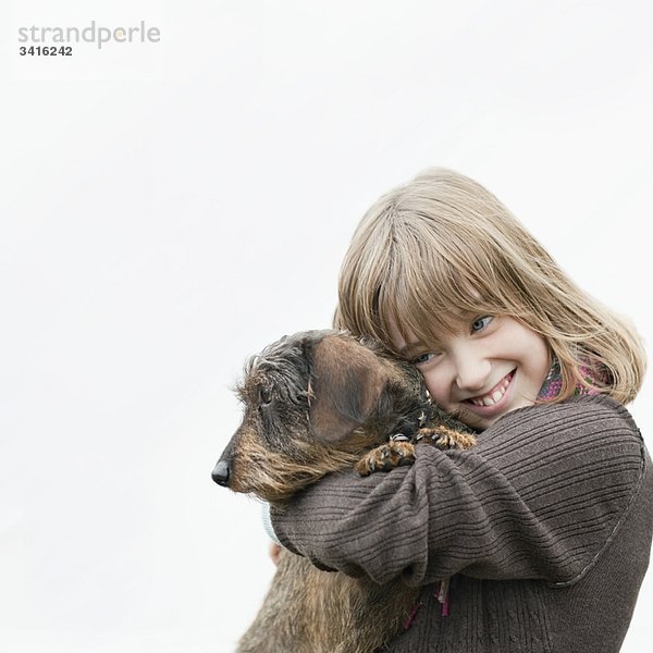 Porträt eines Mädchens  das den Hund in den Armen umarmt.