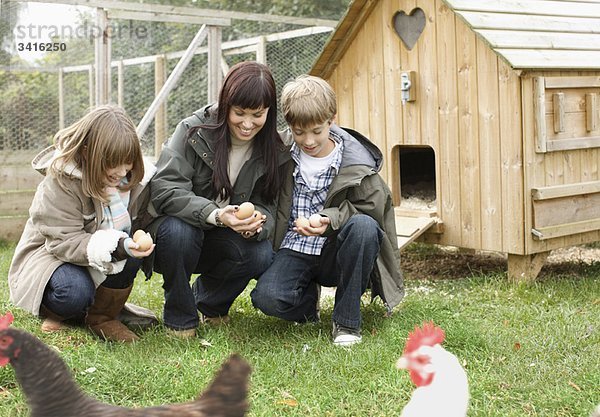 Mutter und Kinder beim Füttern von Hühnern