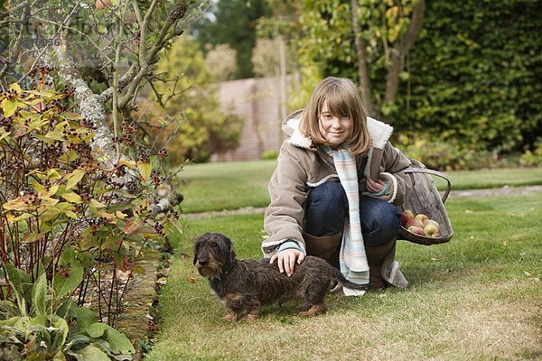 Mädchen mit Korb und Hund im Garten