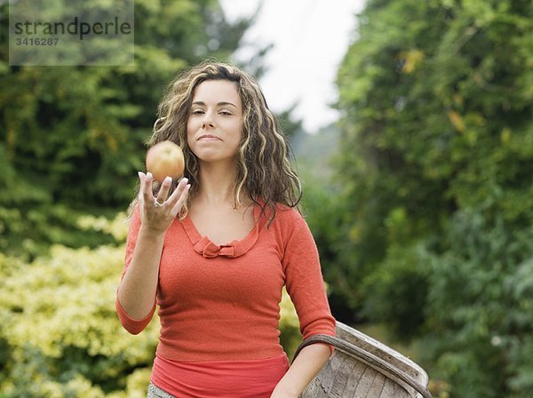 Frau hält Korb mit Apfel in der Hand