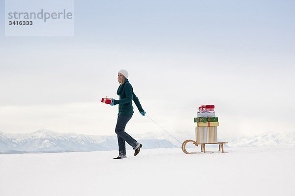 Frau zieht Weihnachtsgeschenke auf Schlitten