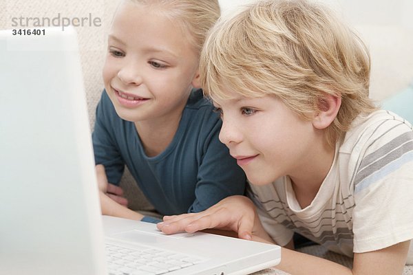 Ein Junge und ein Mädchen  die einen Laptop benutzen.