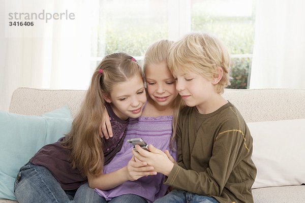 Drei Kinder schauen auf ein Handy