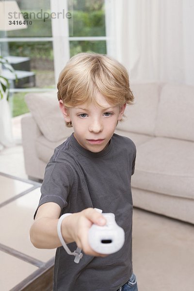 Ein Junge  der eine Spielkonsole zur Kamera zeigt.